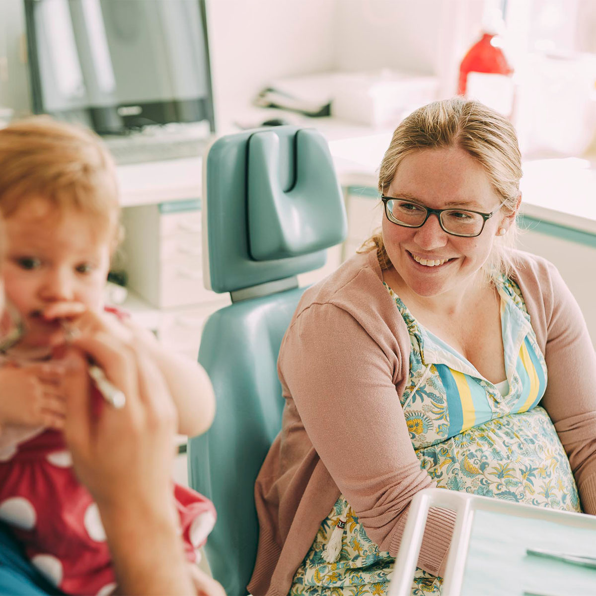 Mutter sieht zu wie Zahnarzt in Emmendingen die Zähne ihres Kindes untersucht
